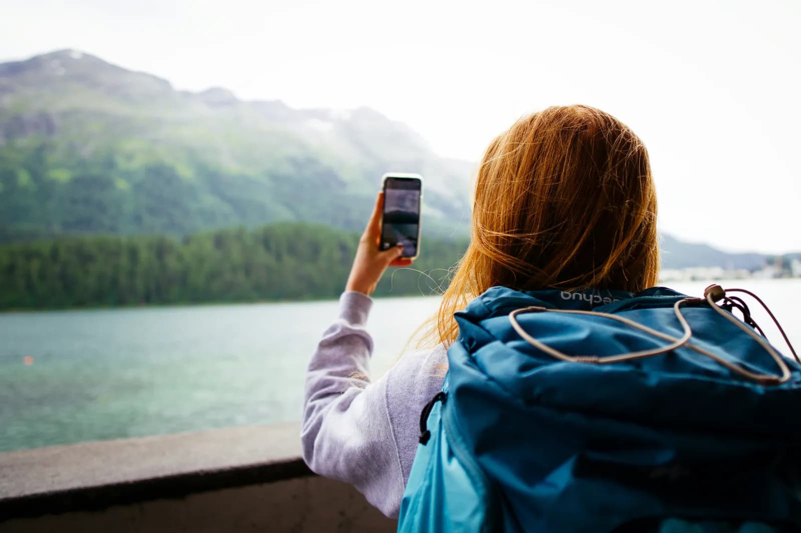 Reiziger maakt een foto met haar telefoon bij een bergmeer in het buitenland